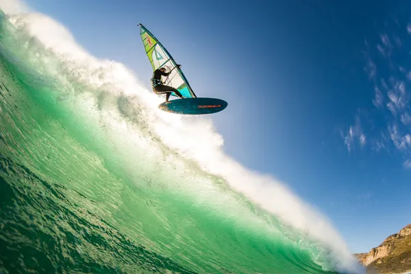 Jung reitet die Welle mit seinem Windsurfboard