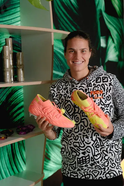 Dzsenifer Marozsan mit Fußballschuhen vorm Regal