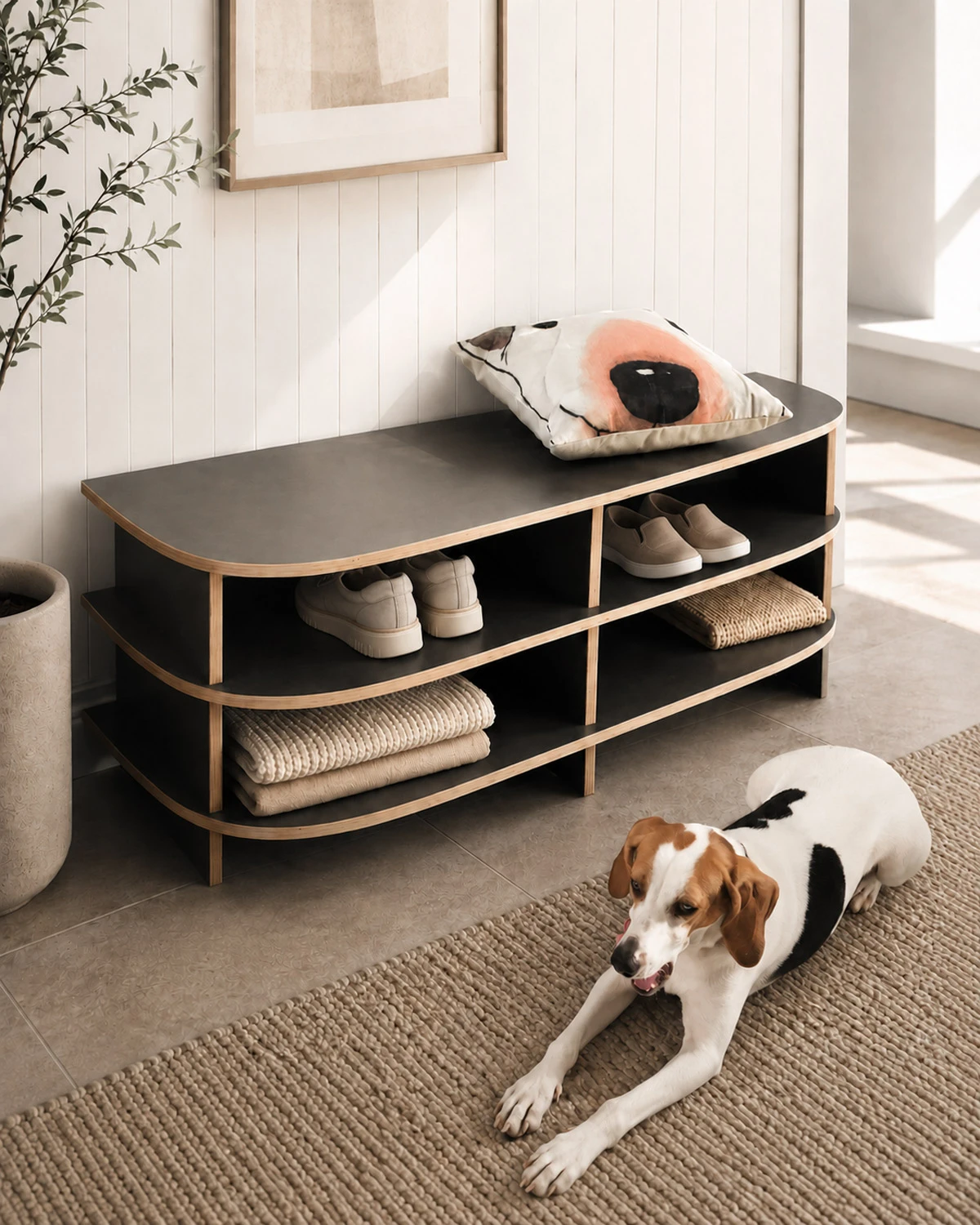 Dark grey hallway bench with wood edge, open compartments, shoe storage, cushion and dog in a modern entryway