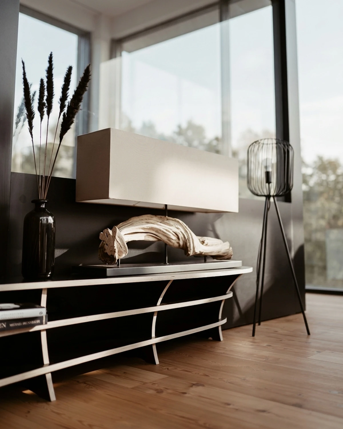 Meuble bas noir au style organique de Kayo, avec des bords en bois et des éléments décoratifs, dans un salon lumineux