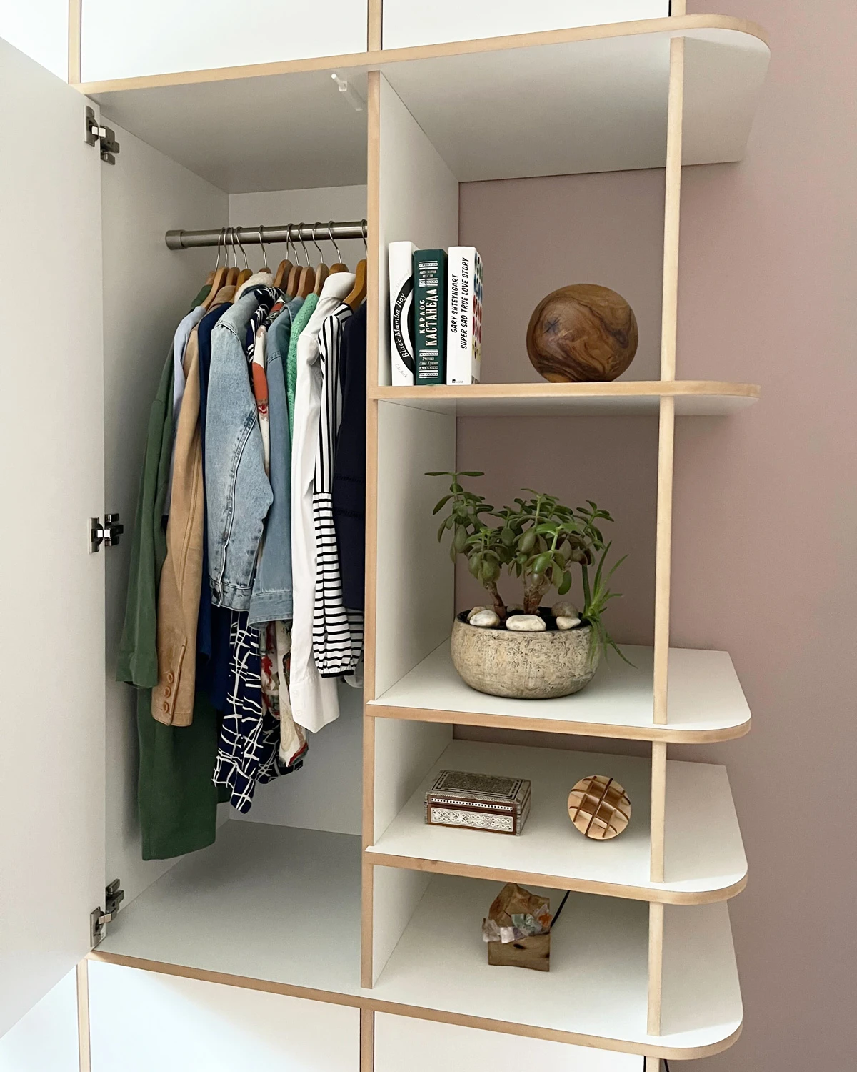 Offene weiße Garderobe mit Kleiderstange, verrundeten Ecken, Holzkante, offenen Fächern, Kleidung und Deko im Detail