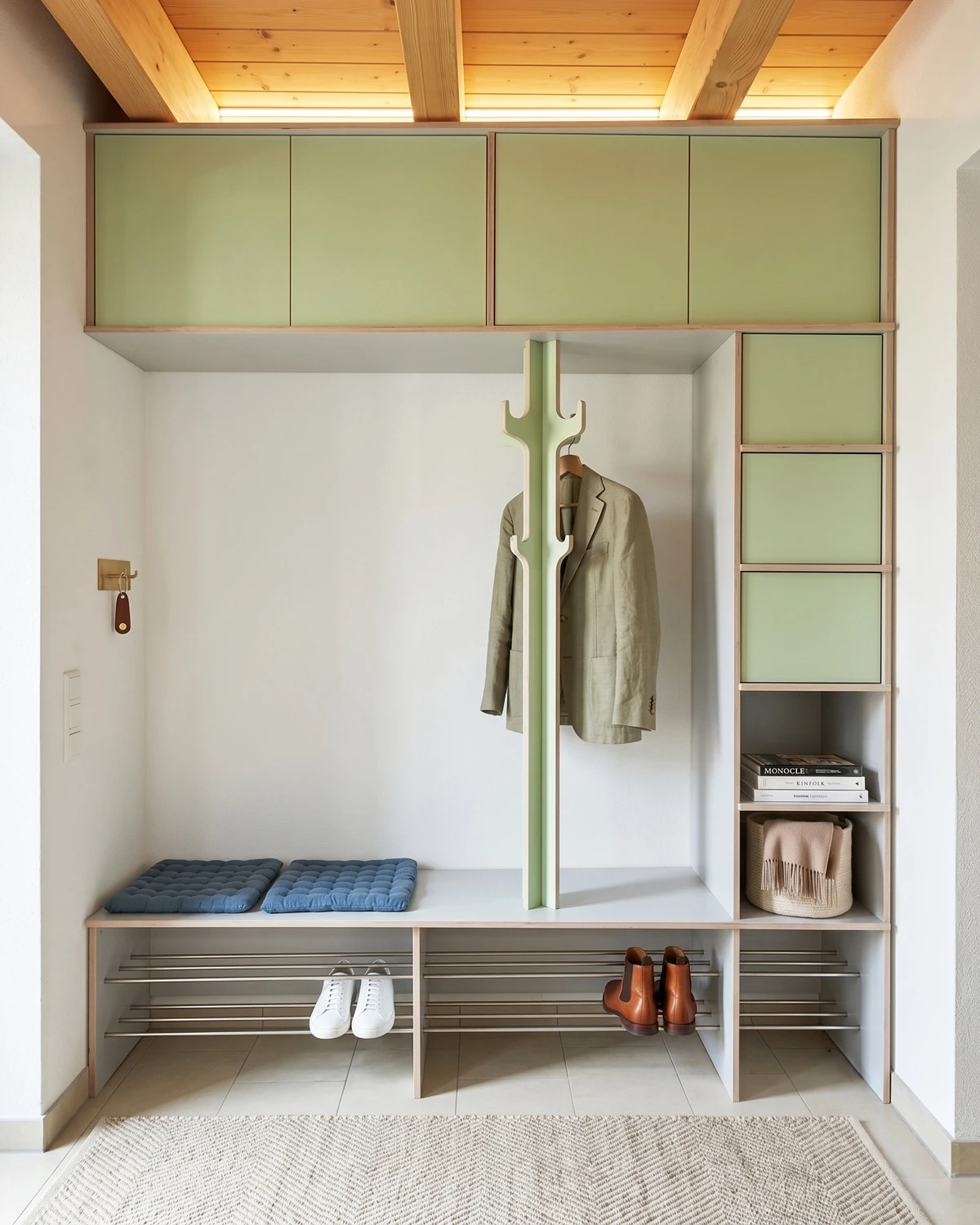 White hallway wardrobe with bench, mint green doors, clothes hooks, shoe storage and storage space in a bright hallway niche