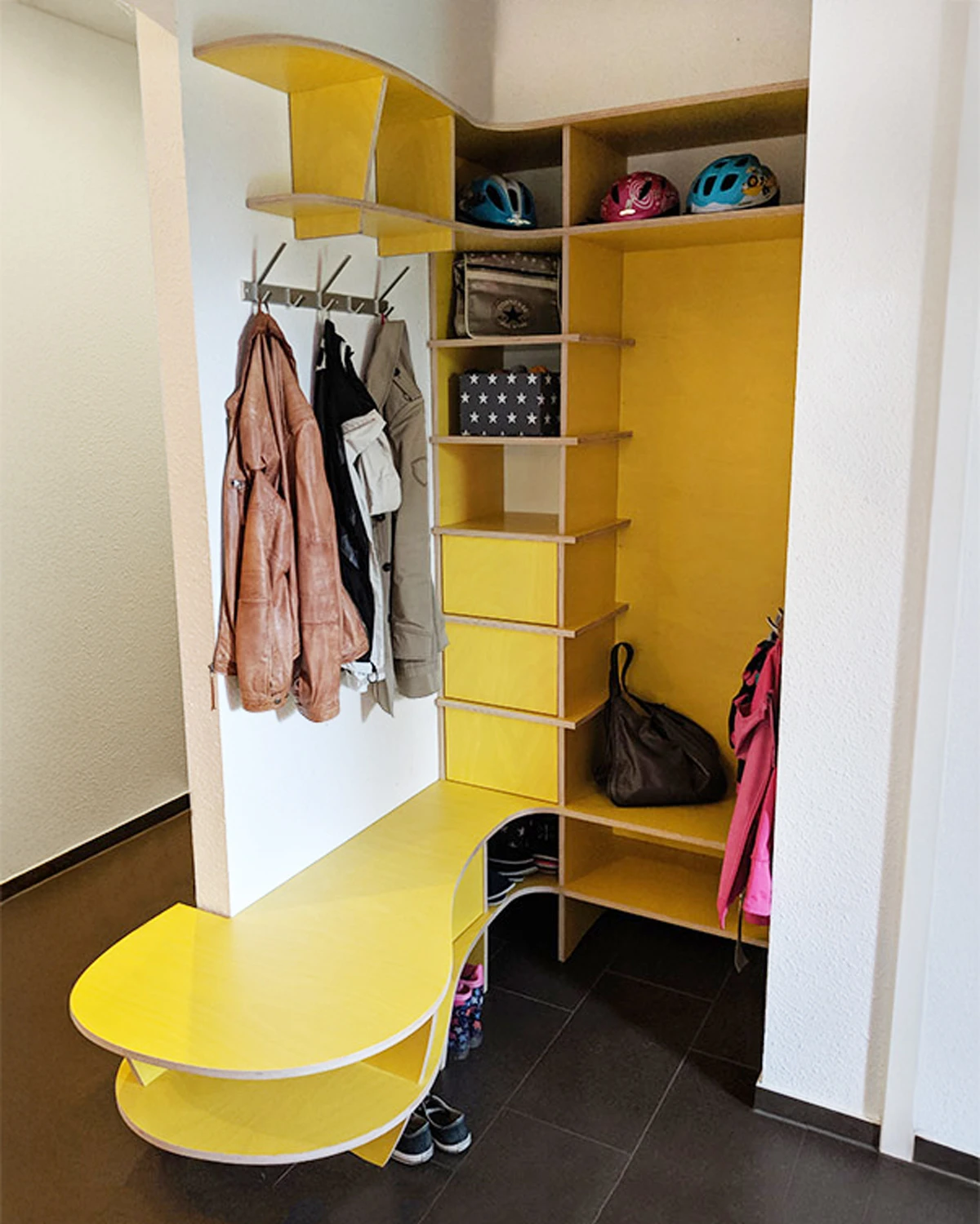 Yellow hallway wardrobe with integrated bench, open compartments, hooks, drawers and storage in a hallway niche